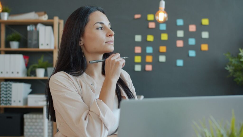 Businesswoman pondering in a contemporary office setting with colorful sticky notes.